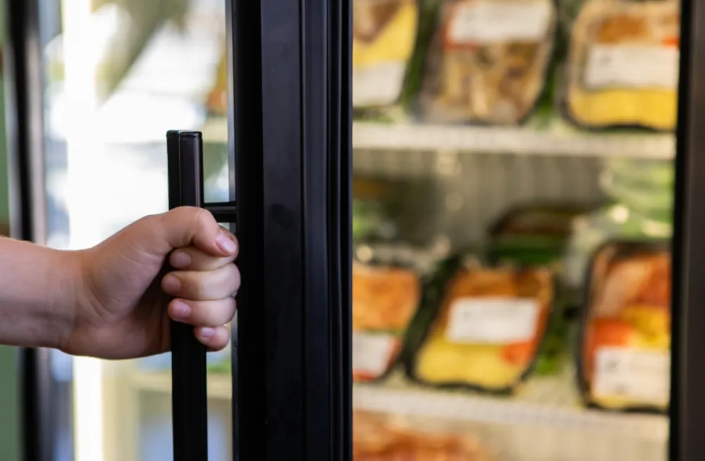 Hand opening the door of a walk-in chiller for food storage in Dubai. Specialist repairs and maintenance for commercial chillers in Dubai.