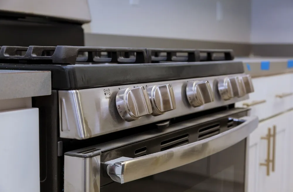 Commercial cooking range being repaired in a kitchen.