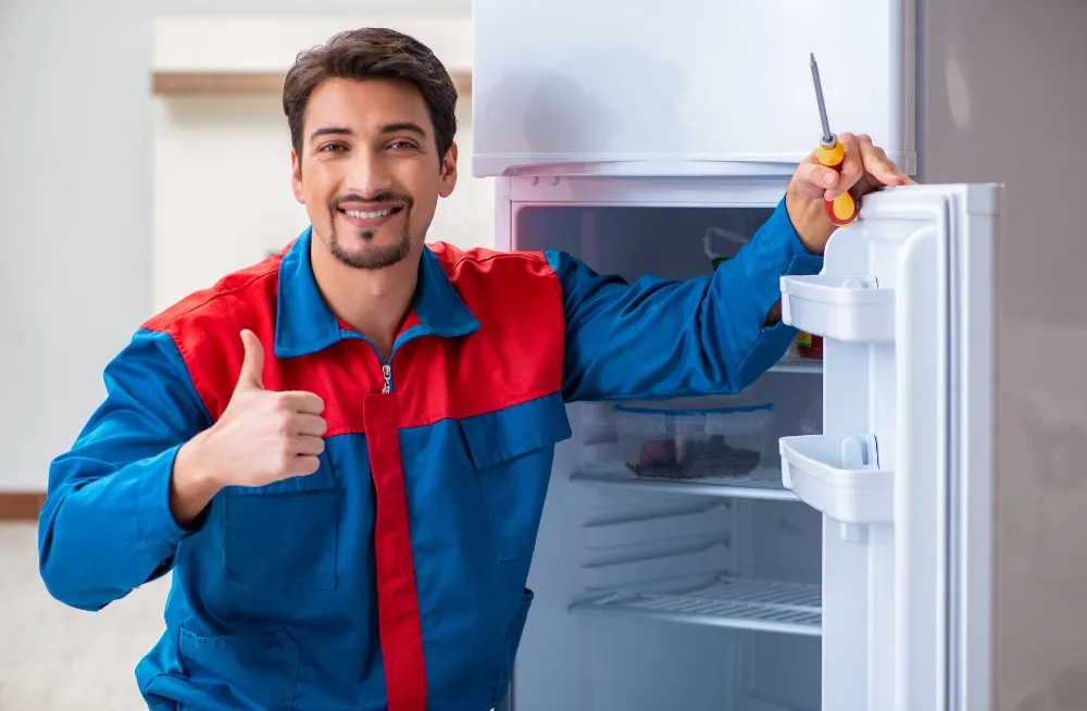 Happy fridge repair technician giving a thumbs up after fixing a commercial refrigerator – Professional fridge repair services in Dubai.