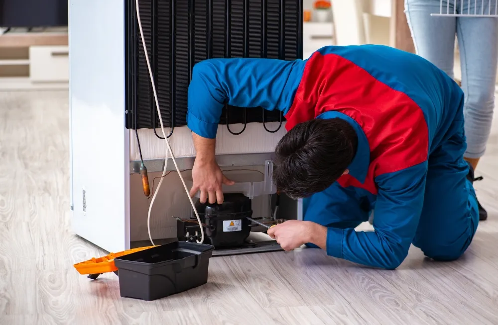 Fridge repair technician fixing a compressor in a commercial fridge – Expert fridge repair service in Dubai.