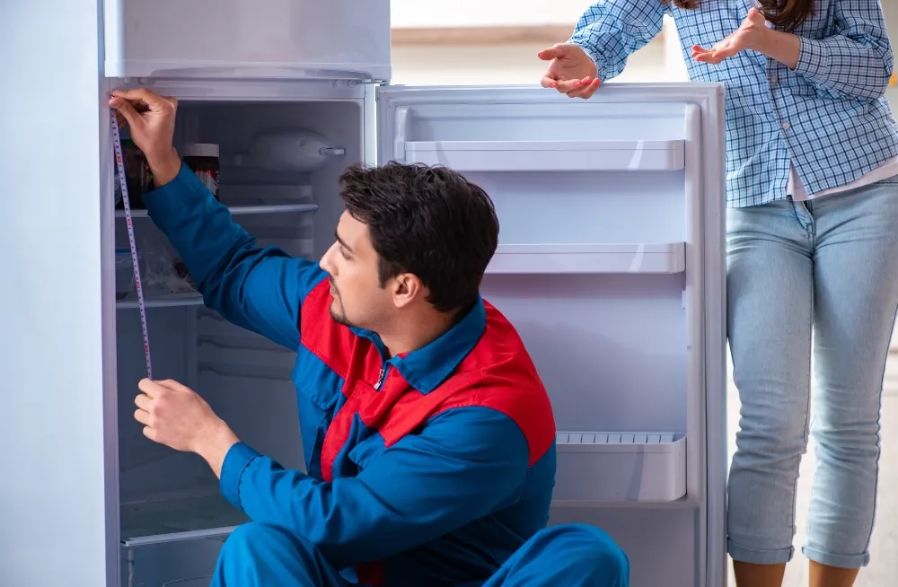 ridge repair technician measuring a commercial refrigerator with a customer present – Professional fridge repair services in Dubai.