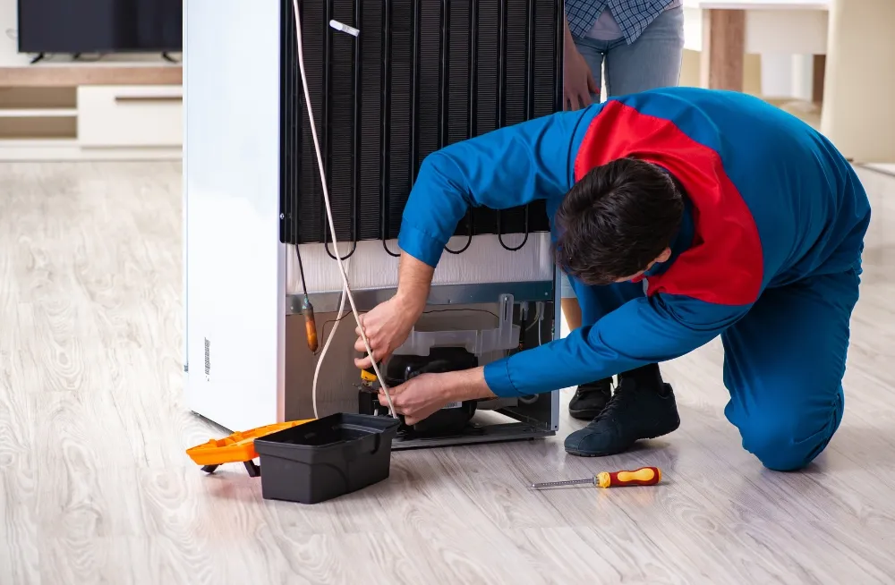 Fridge repair technician fixing the compressor of a commercial refrigerator – Professional fridge repair services in Dubai.