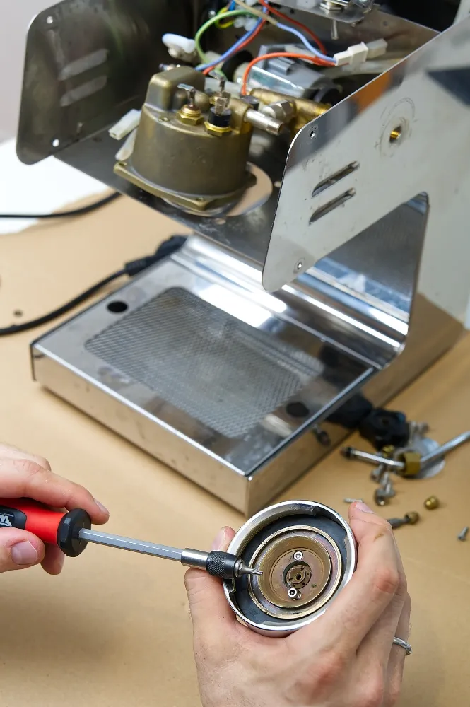 Technician repairing a commercial coffee machine component with precision, showcasing expert coffee machine repair services in Dubai by Prime Pro Technical.