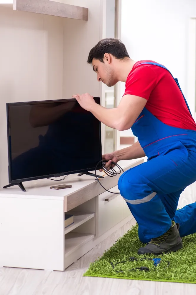 Technician fixing TV connections and setup during professional home service in Dubai