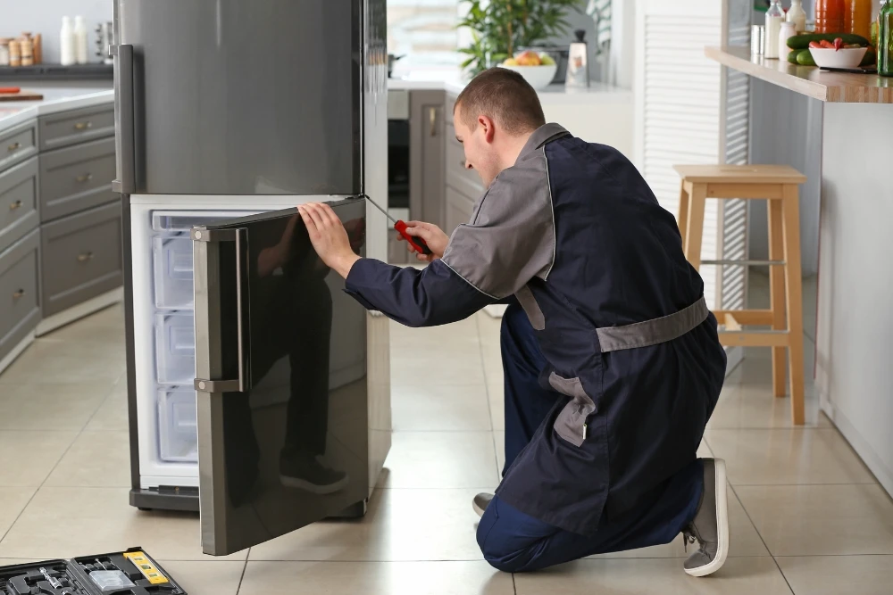 Professional appliance repair technician working on refrigerator