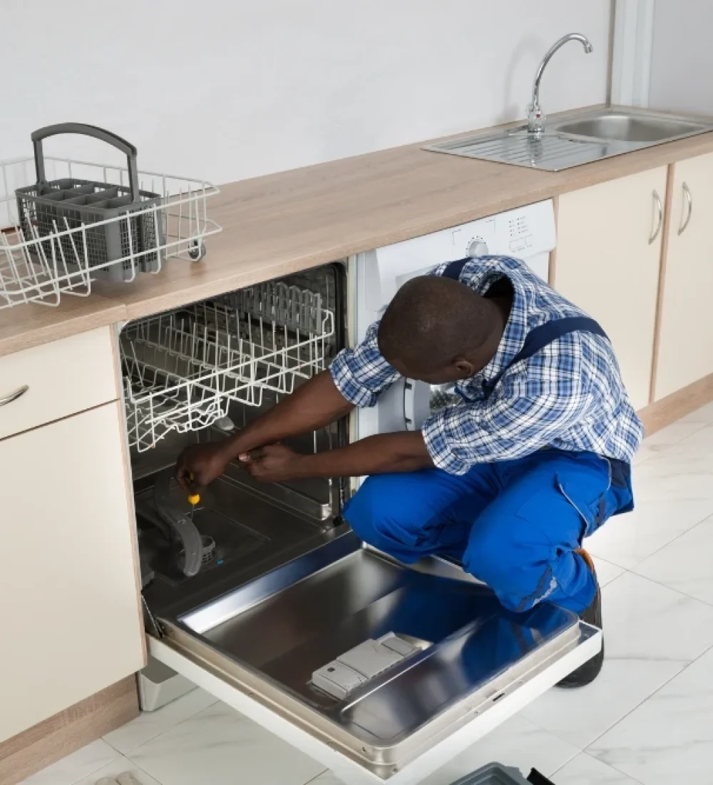 Technician repairing a built-in dishwasher in a modern kitchen, providing professional dishwasher repair services across the UAE.